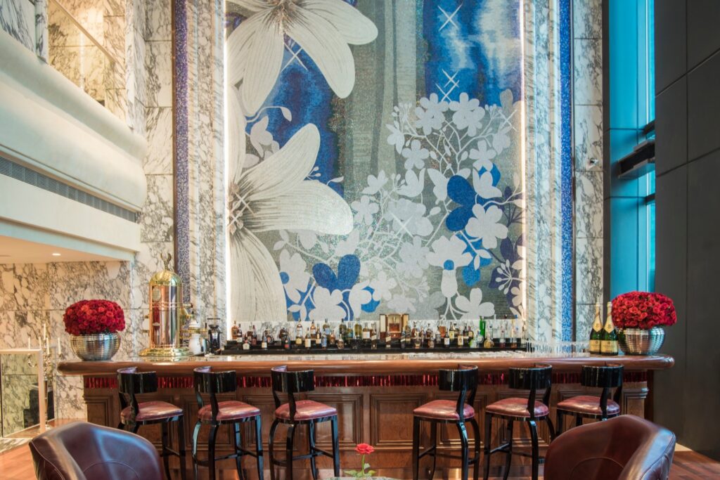 Luxury hotel bar interior featuring custom artistic glass mosaic wall by JNJMosaic