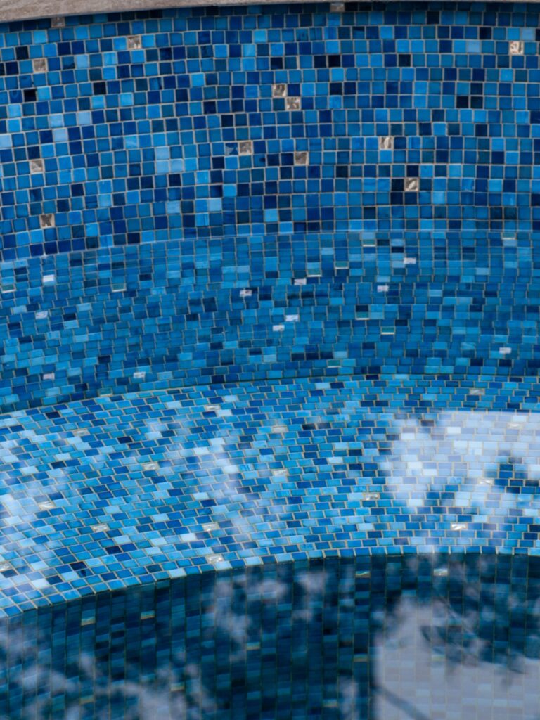 How to Choose Pool Mosaic Tiles: A Project-Based Guide 4 Small blue mosaic tiles fitted across a curved pool wall and rounded bench