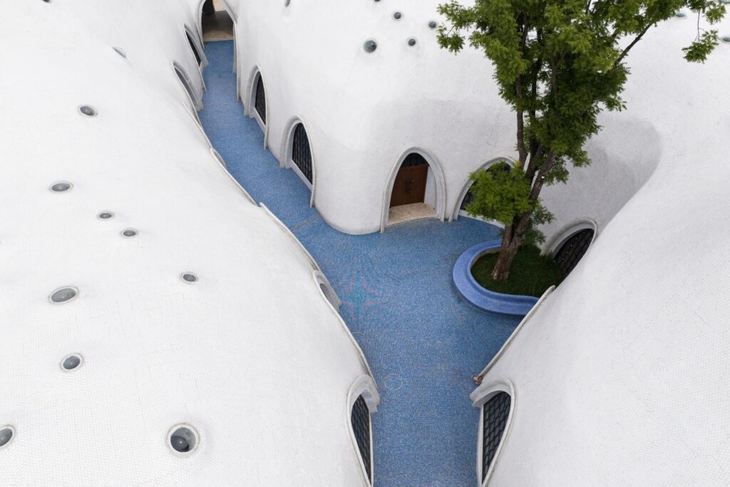 Aerial view of a blue mosaic courtyard and tree-lined corridor at The Cloud Art Palace