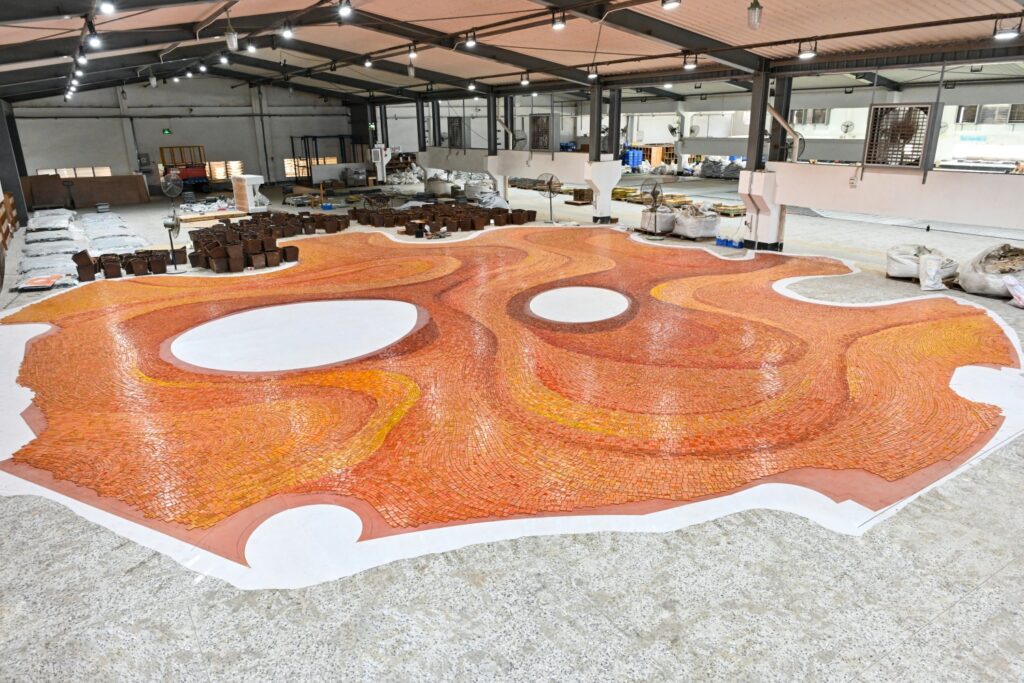 Full-scale assembly of the red earth-inspired mosaic artwork in the JNJMosaic workshop