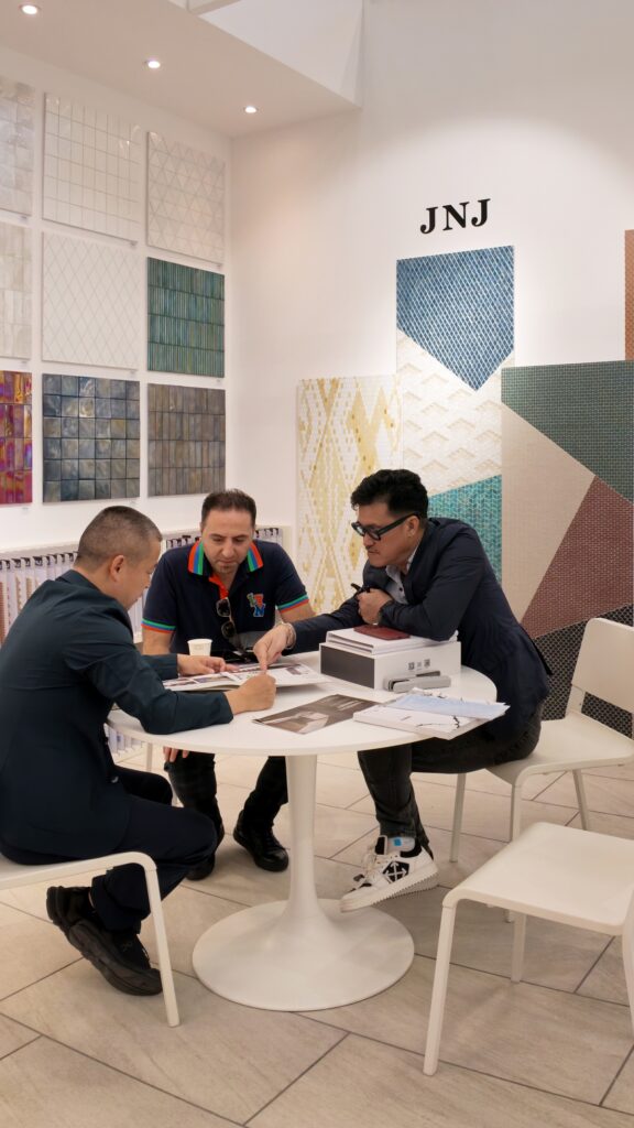 Inside the JNJMosaic Booth at Cersaie 2026: Art, Materials and Meaningful Conversations 10 Visitor reviewing a JNJ Mosaic sample board during a booth consultation