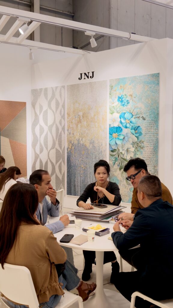 Inside the JNJMosaic Booth at Cersaie 2026: Art, Materials and Meaningful Conversations 11 Visitor reviewing a JNJ Mosaic sample board during a booth consultation