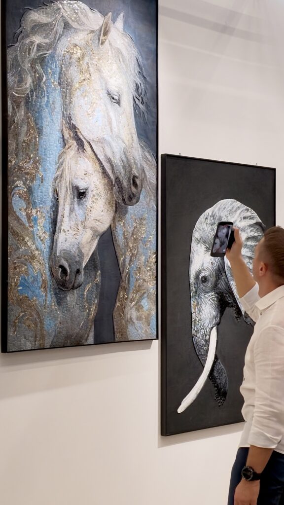 Inside the JNJMosaic Booth at Cersaie 2026: Art, Materials and Meaningful Conversations 5 Visitor photographing horse and elephant mosaic artworks at the JNJ booth