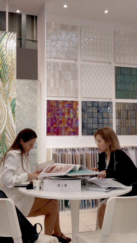Inside the JNJMosaic Booth at Cersaie 2026: Art, Materials and Meaningful Conversations 12 JNJ representative reviewing mosaic catalogues with a visitor