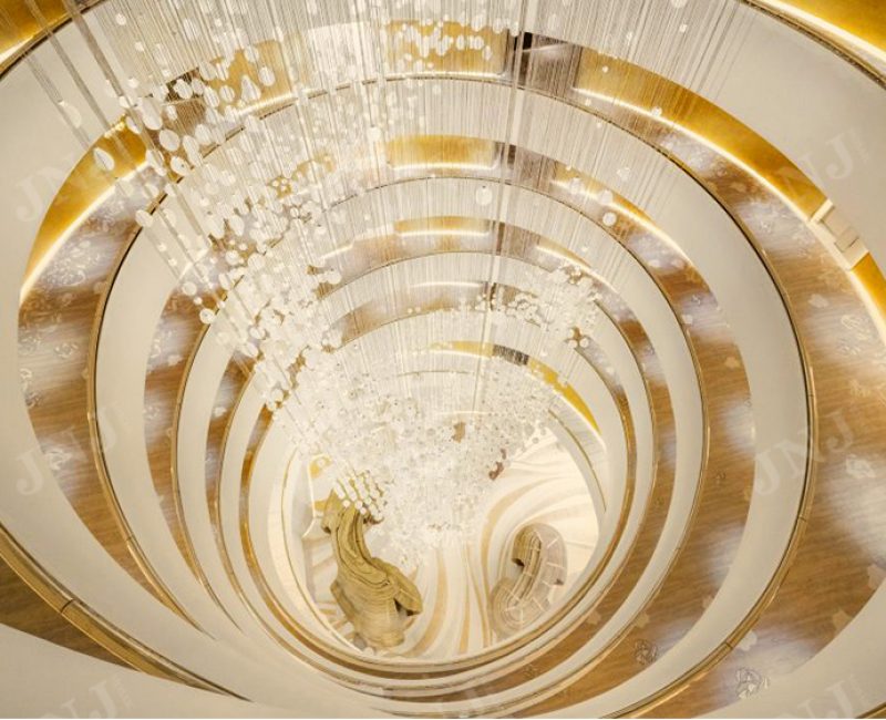 Top-down view of the iconic grand chandelier with 24K gold mosaic walls in the Fairmont Doha atrium