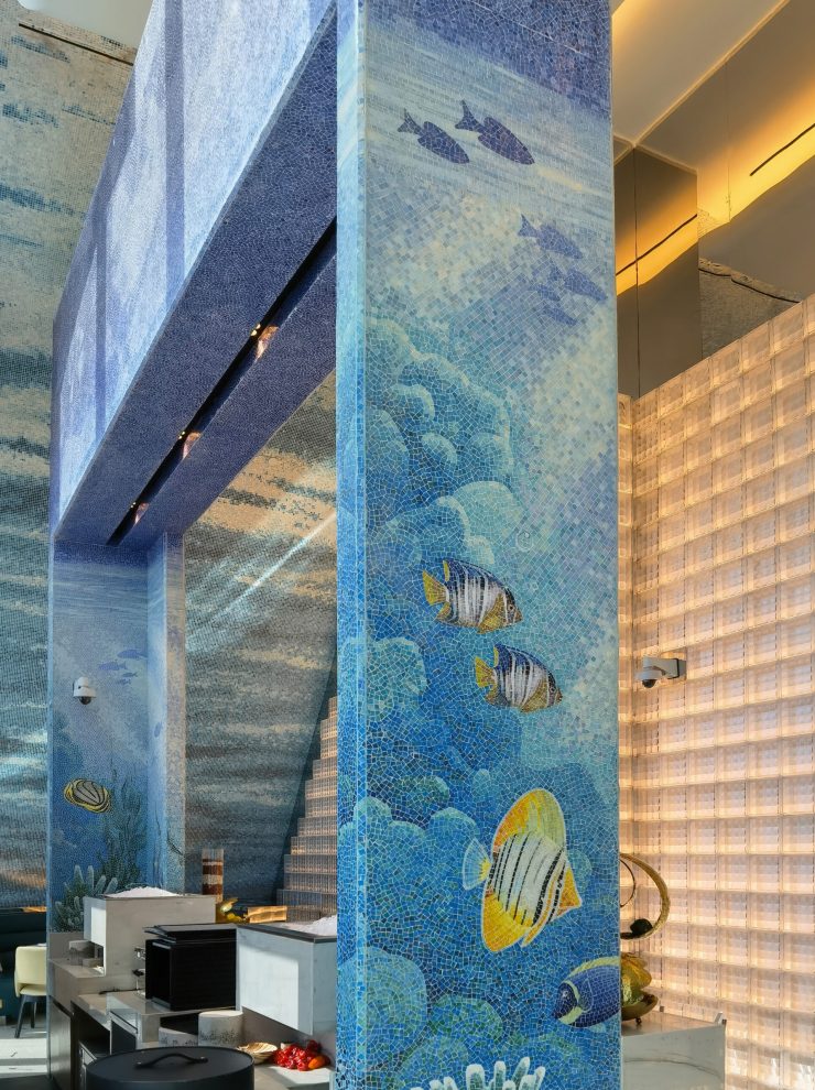 ibrant mosaic art wall depicting tropical fish and colorful coral reefs in a luxury restaurant