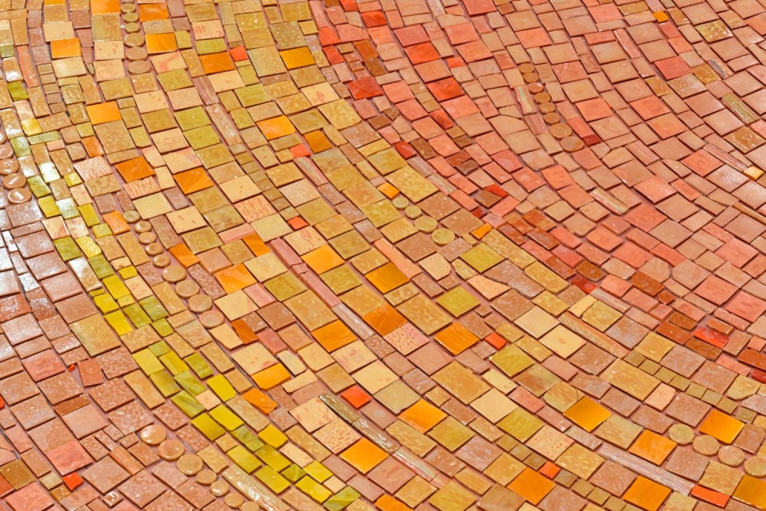 Close-up of a handcrafted orange glass mosaic composition with flowing lines