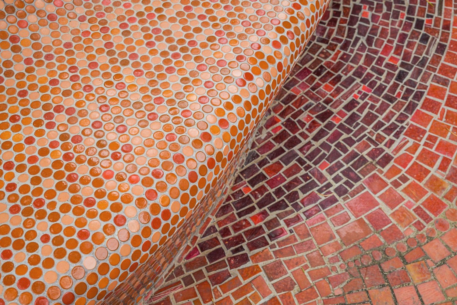 Close-up of round and rectangular custom glass mosaics across curved seating and flooring