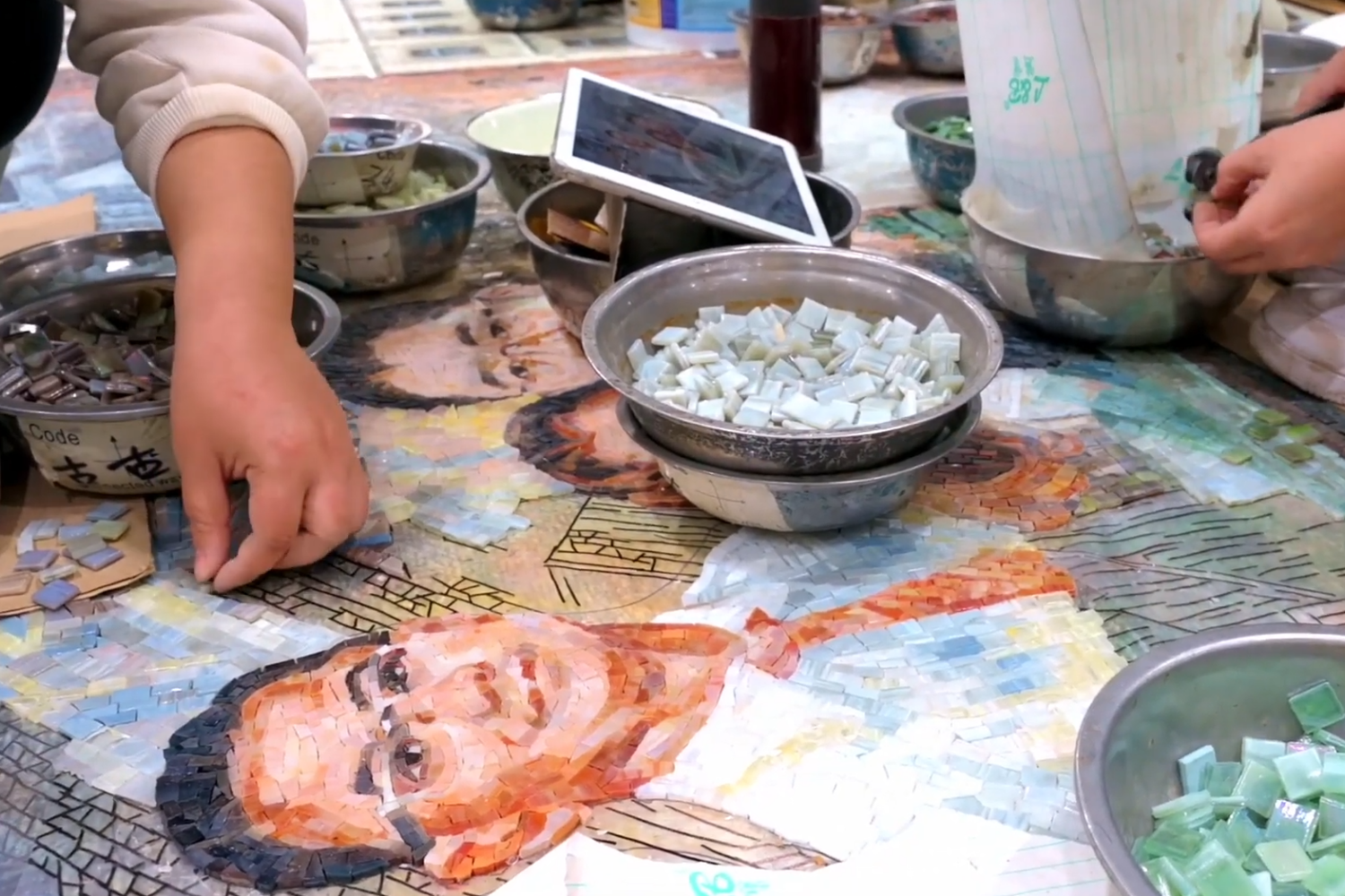 Close-up of hand-cut glass mosaic tiles, showing irregular geometric pieces perfectly replicating the delicate brushstrokes of the oil painting.
